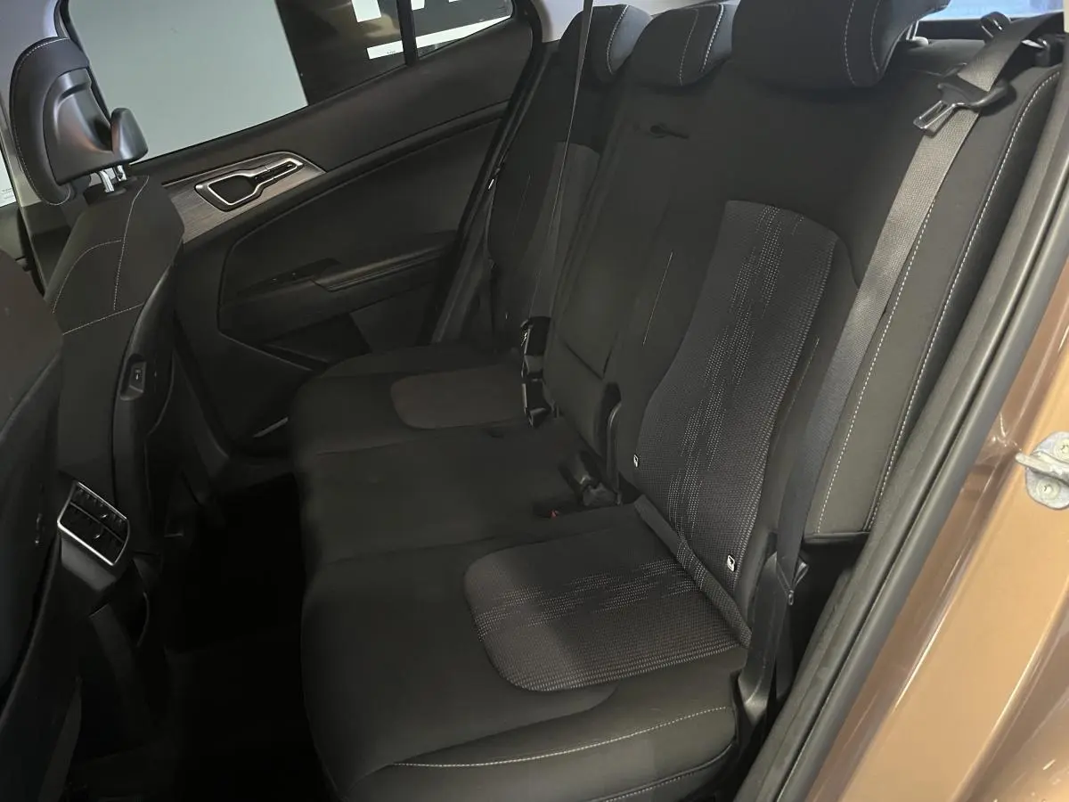 Vue côté droit de la banquette arrière noire du Kia Sportage marron 2022 avec appuie-têtes et ceintures visibles.