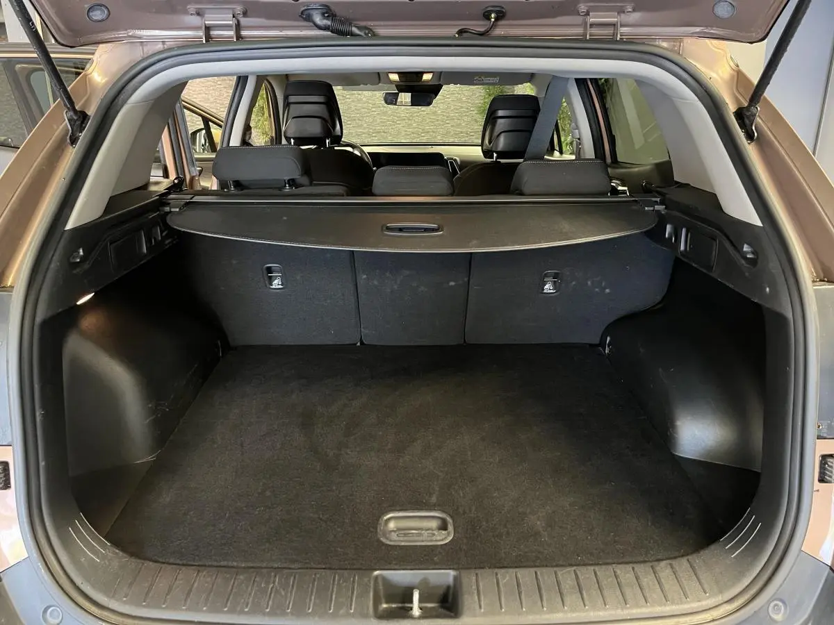 Coffre ouvert d'un KIA Sportage marron 2022, vue arrière montrant la plage arrière et les sièges noirs.