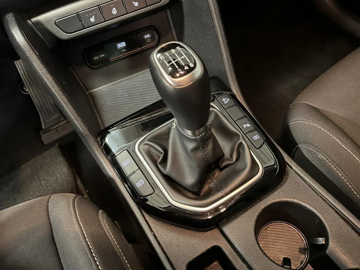 Gros plan sur la console centrale noire du Kia Sportage 2022 avec levier de vitesse manuel et boutons fonctionnels.