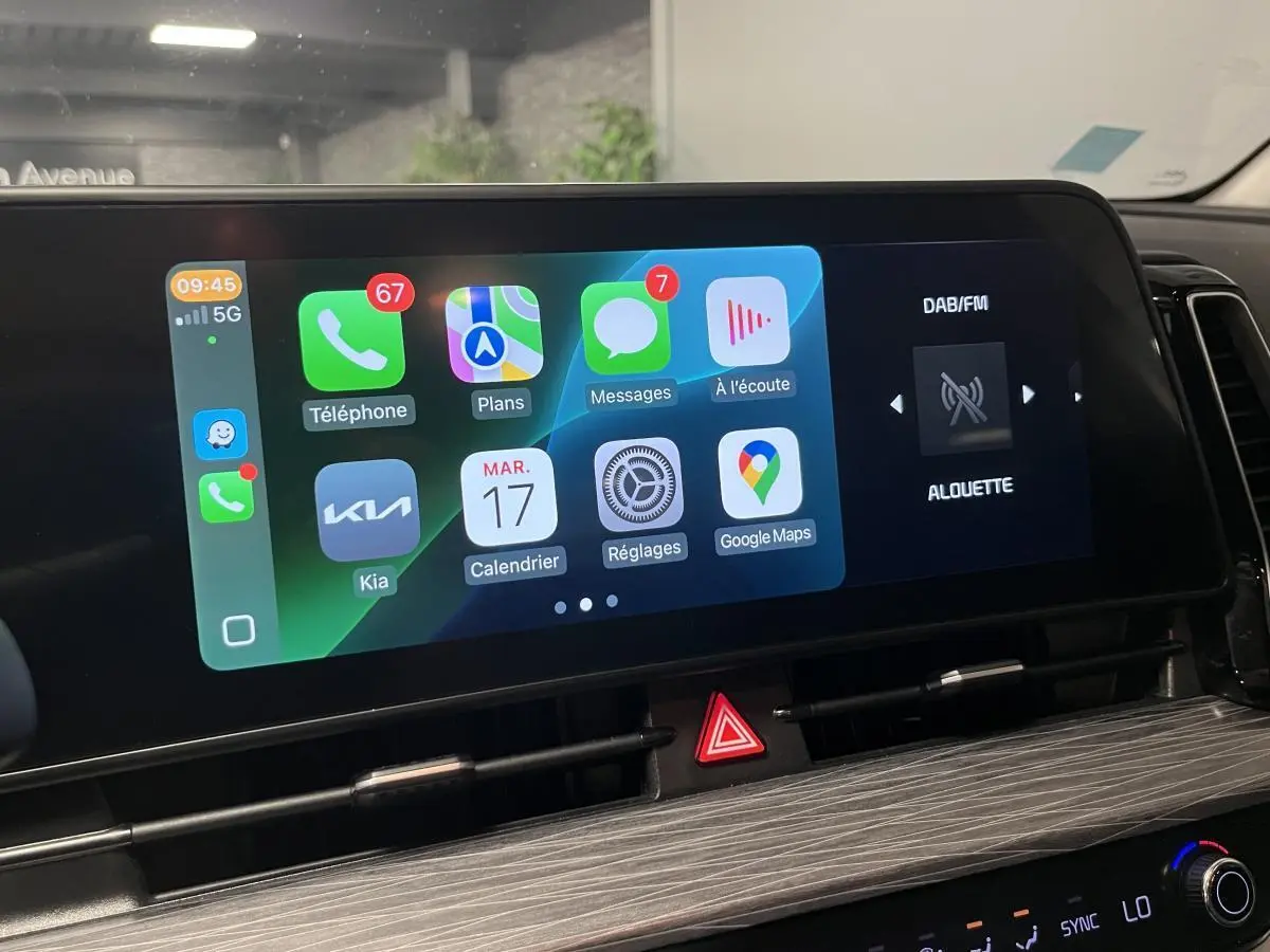 Écran tactile central du Kia Sportage 2022 montrant interface Apple CarPlay et radio DAB/FM en intérieur noir.
