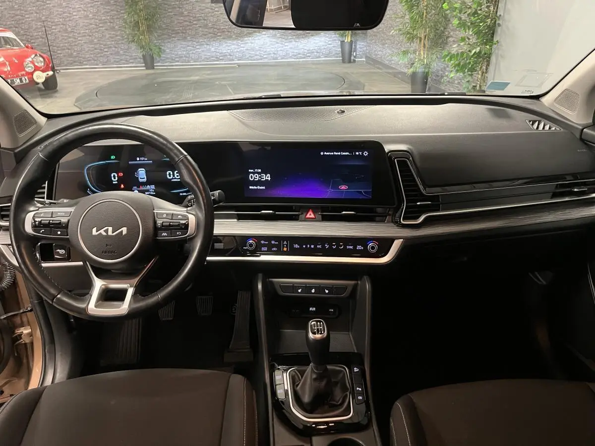 Intérieur du Kia Sportage 2022, vue de face sur tableau de bord noir avec écran tactile et levier de vitesses manuel.