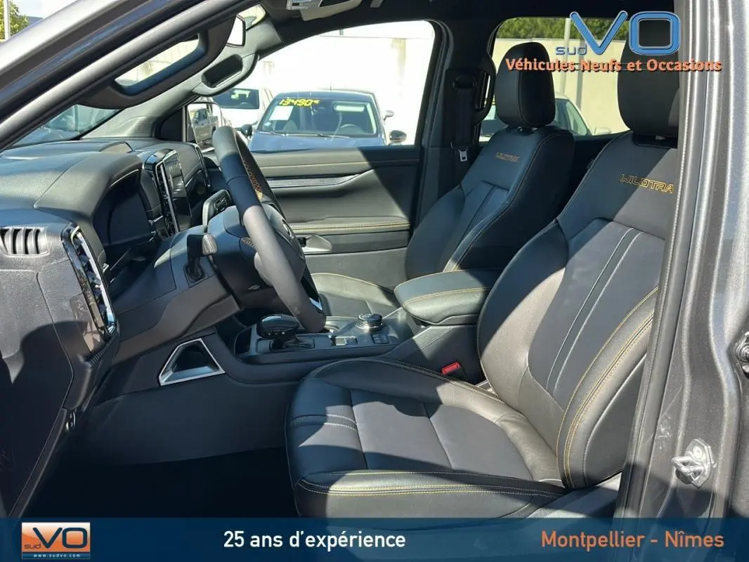 Vue intérieure côté conducteur du Ford Ranger Wildtrak gris 2025, avec sièges cuir noirs brodés et console centrale équipée.