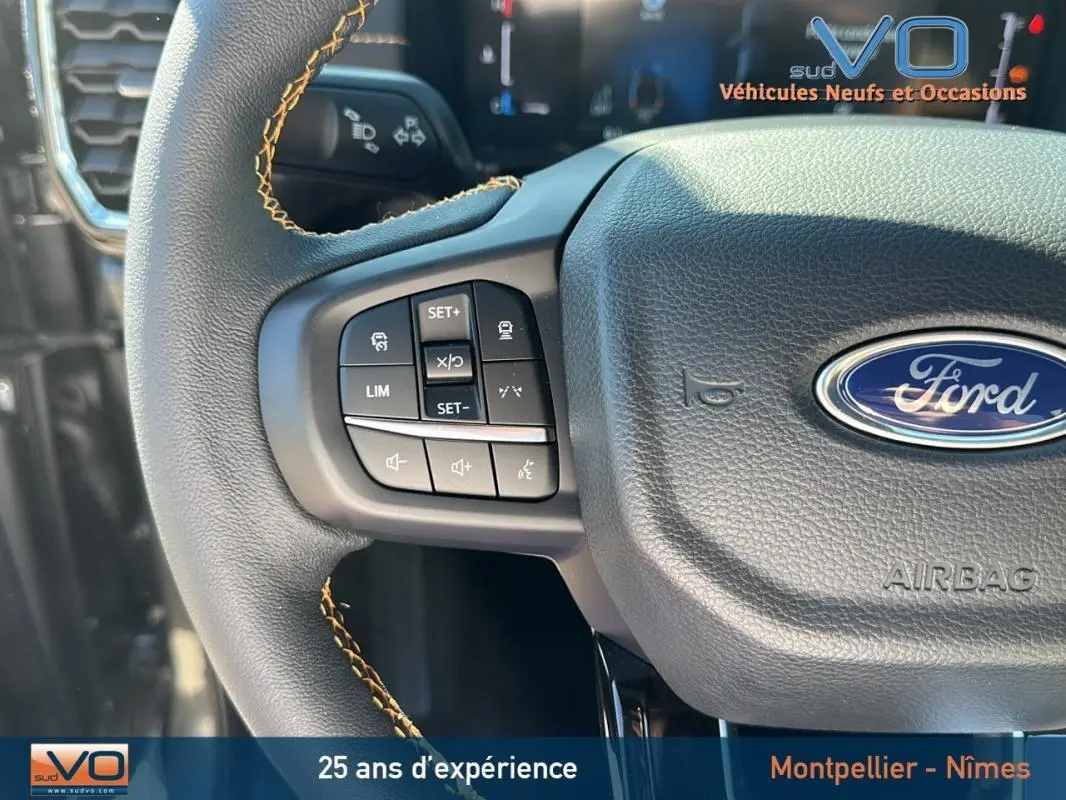 Gros plan sur le volant multifonctions noir avec surpiqûres jaunes du Ford Ranger gris 2025, mettant en valeur les commandes intégrées.