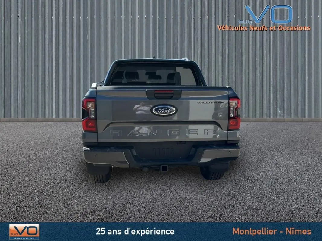 Vue arrière d'un Ford Ranger gris Wildtrak X 2025 avec hayon fermé et feux arrière allumés.