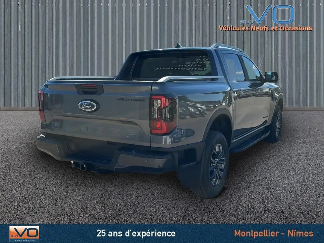 Ford Ranger Wildtrak gris vu en 3/4 arrière droit avec barres de toit et vitres surteintées.