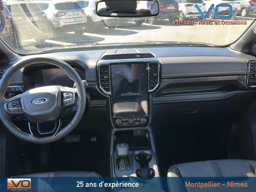 Vue intérieure avant du Ford Ranger Wildtrak 2025 avec volant multifonctions, écran tactile vertical et sellerie noire.