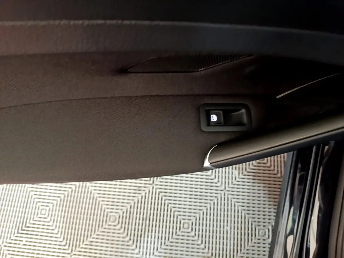 Poignée intérieure de la porte côté droit d'une Volkswagen Golf noire, vue en gros plan depuis l'intérieur.