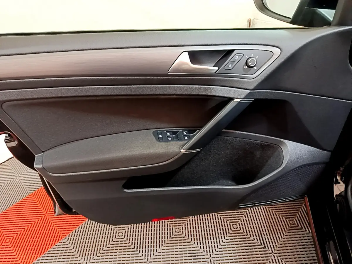 Vue rapprochée de la porte avant gauche noire de la Volkswagen Golf 2018, avec commandes électriques et insert décoratif gris.