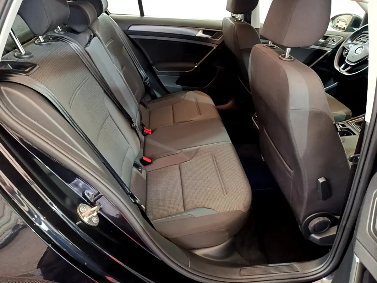 Vue intérieure côté droit sur la banquette arrière et l'avant d'une Volkswagen Golf noire de 2018, sièges tissu gris.