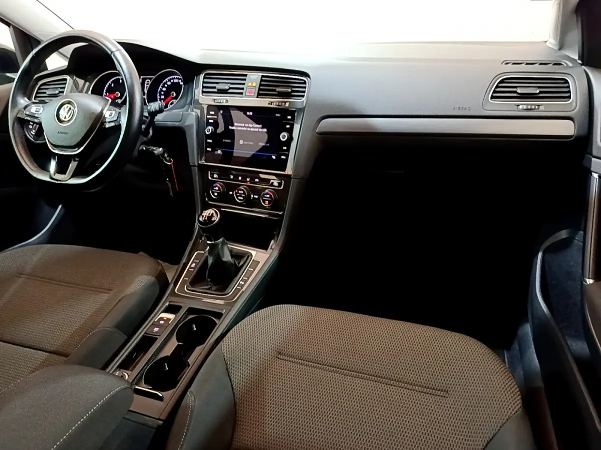 Intérieur de Volkswagen Golf 1.6 TDI 2018 vu côté passager, tableau de bord noir avec écran tactile et boîte manuelle.