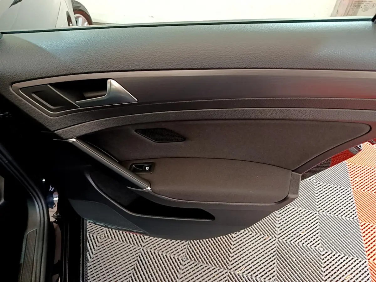 Gros plan sur la porte intérieure côté conducteur noire de la Volkswagen Golf 2018 avec poignée argentée et commande de vitre.