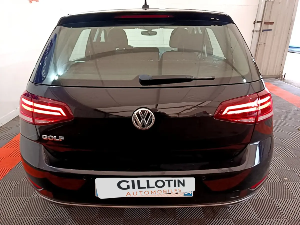 Vue arrière d'une Volkswagen Golf noire de 2018 avec feux LED allumés dans un garage fermé.