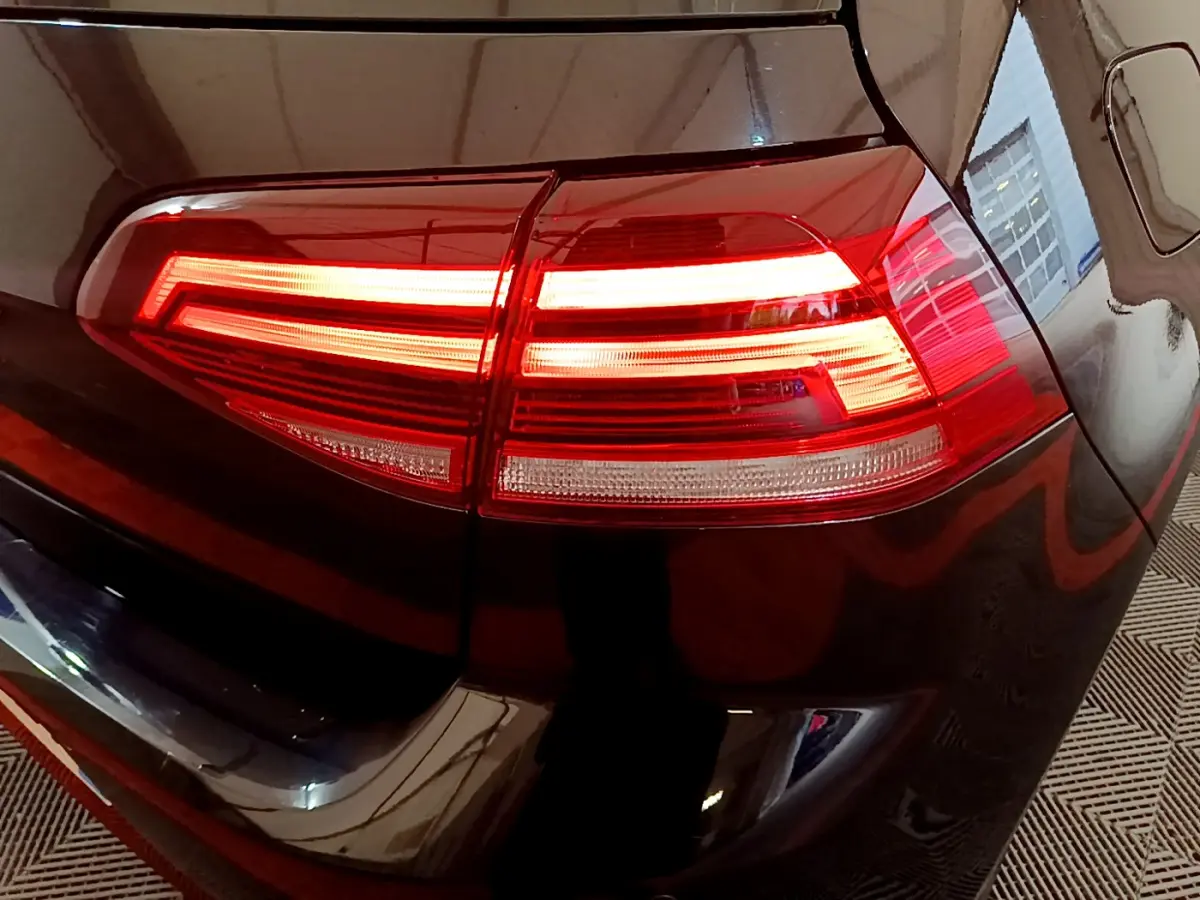 Gros plan sur le feu arrière droit allumé d'une Volkswagen Golf noire, soulignant ses lignes LED distinctives.