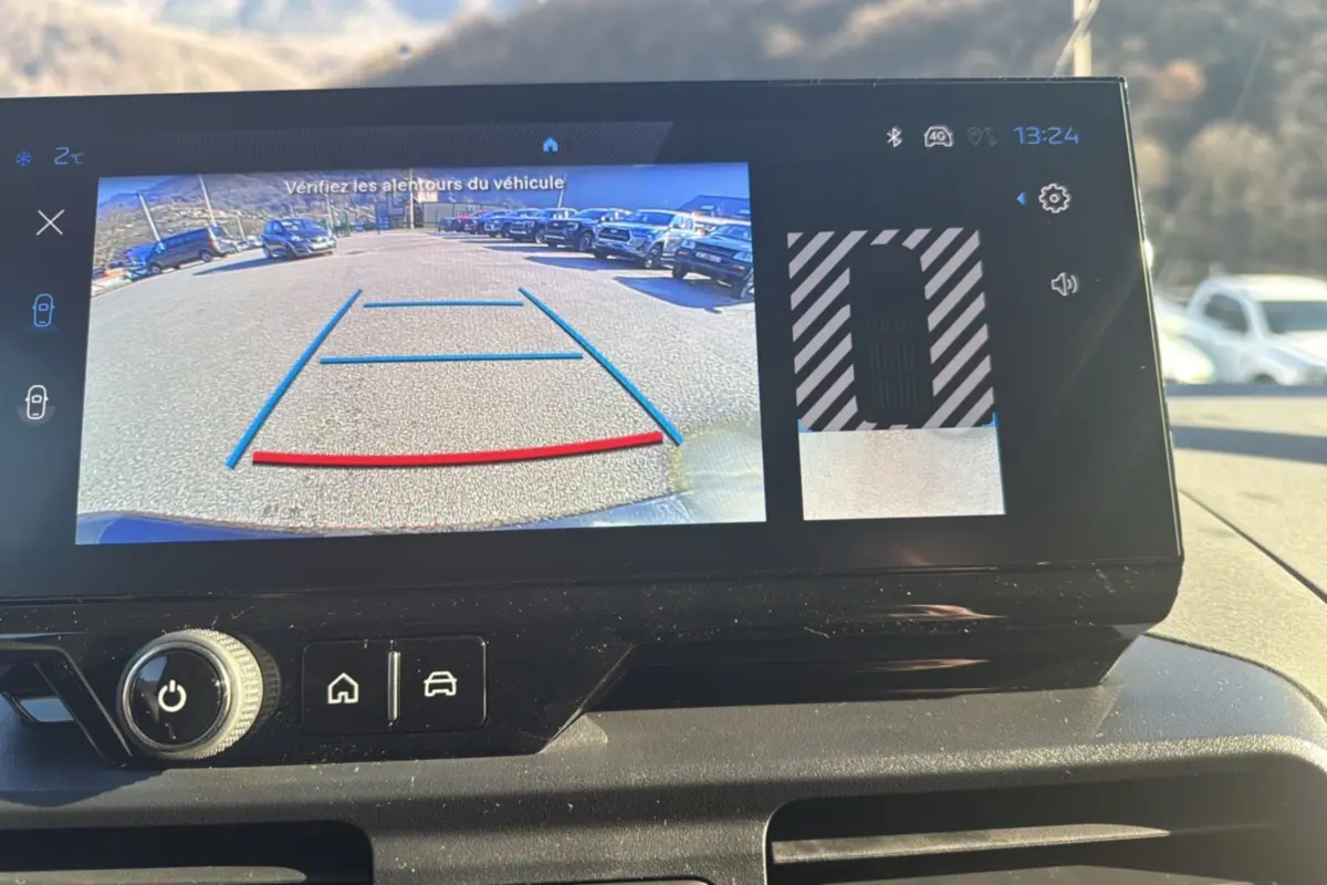 Écran tactile intérieur montrant la caméra de recul avec vue arrière et aide au stationnement du Peugeot Rifter noir perla nera.