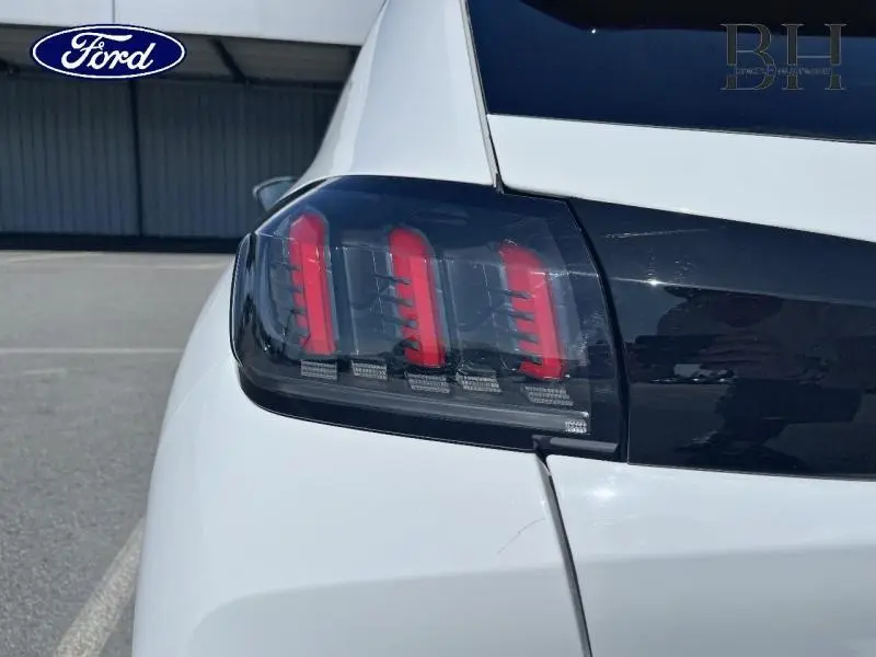 Gros plan sur le feu arrière droit rouge et noir d'une Peugeot 208 blanche Banquise, vue arrière côté droit.