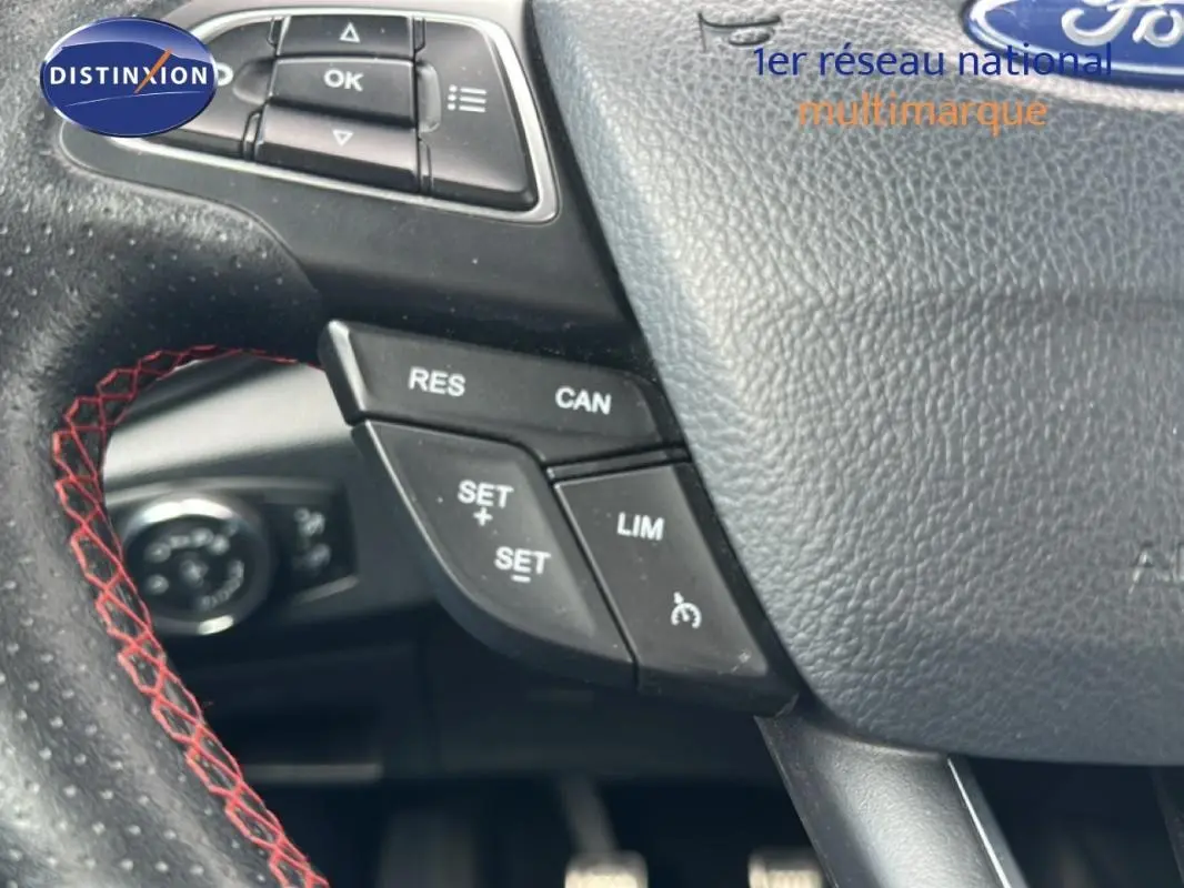 Gros plan sur le volant en cuir noir avec surpiqûres rouges du Ford EcoSport gris clair, boutons de régulateur de vitesse visibles.