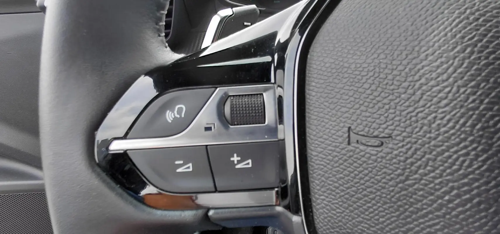 Gros plan sur les commandes de volume et appel vocal sur le volant noir du Peugeot 2008 Hybrid 145 e-DCS6 Style 2025.