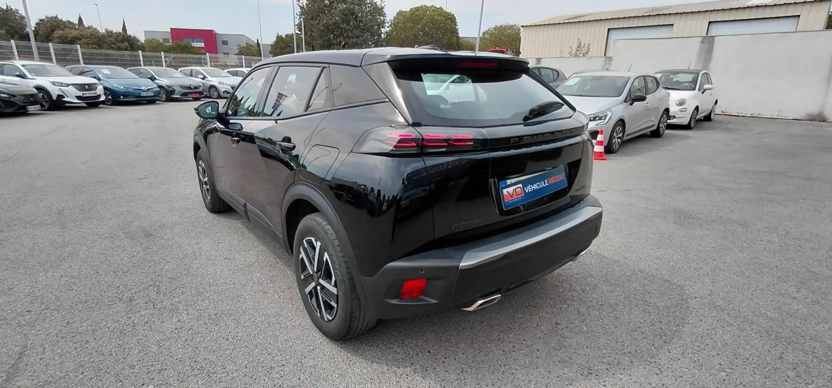 Vue 3/4 arrière droite d’un Peugeot 2008 Hybrid 145 noir, avec feux arrière à effet griffes et jantes alliage.