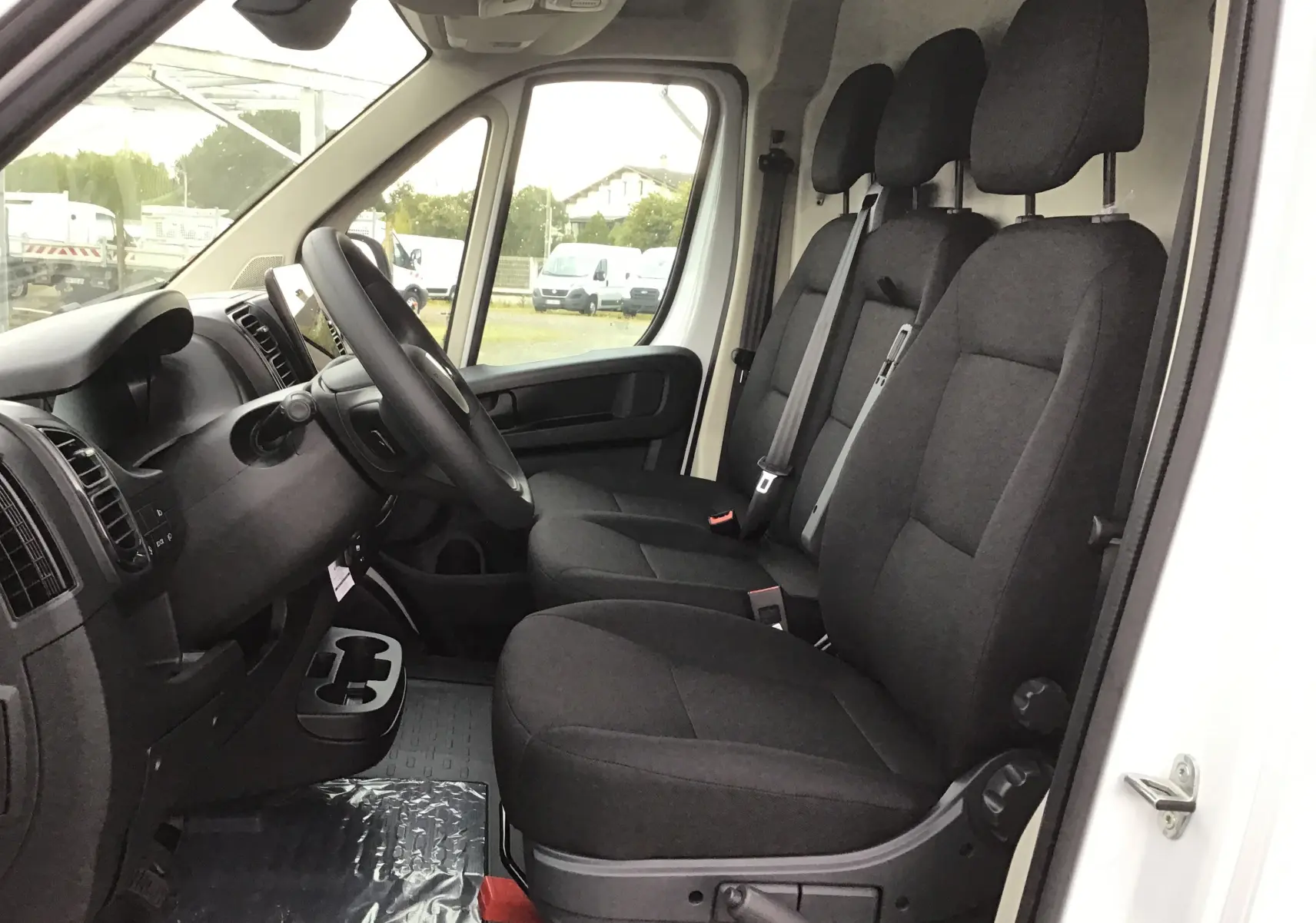 Vue intérieure côté conducteur du Peugeot Boxer Fourgon blanc 2025, montrant les sièges noirs et le tableau de bord.