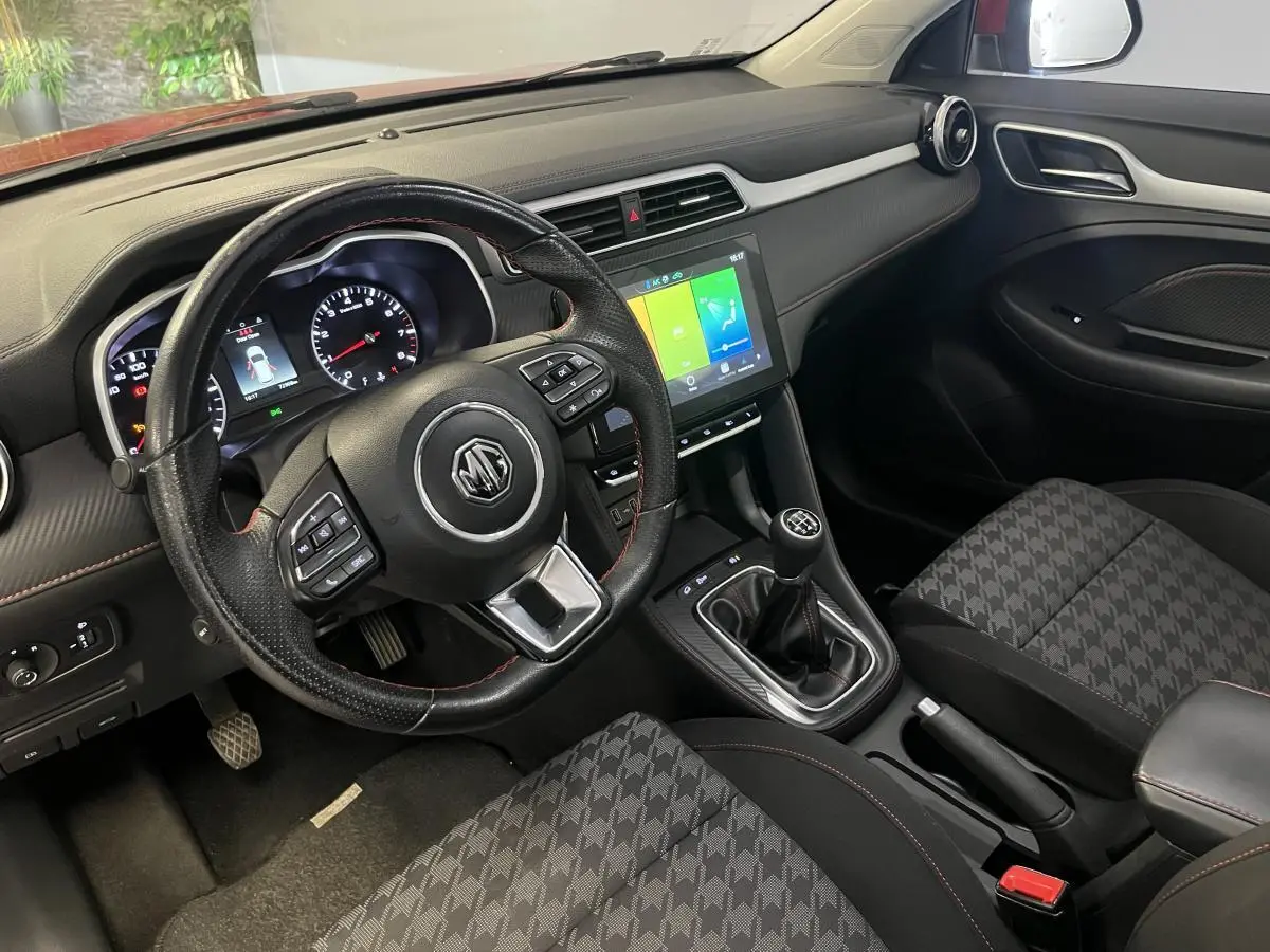 Intérieur de MG ZS 2022 vu côté conducteur, volant cuir avec surpiqûres rouges et écran tactile central.
