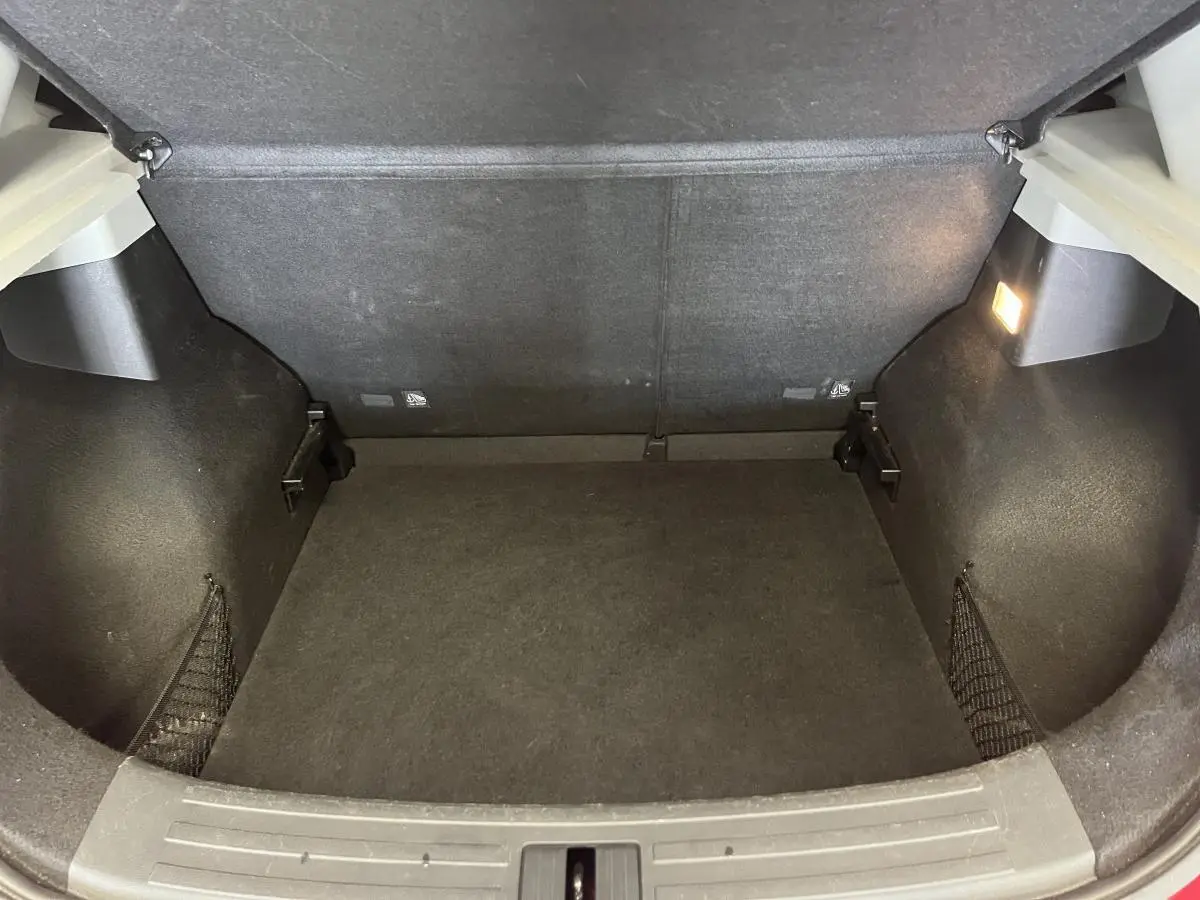 Coffre vide vu de l'arrière d'un MG ZS rouge 2022, avec éclairage intérieur et filets latéraux de rangement.