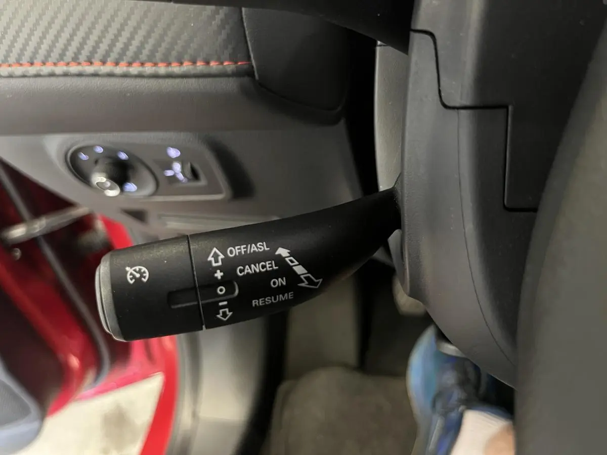 Le levier de régulateur de vitesse du MG ZS rouge 2022 visible côté gauche du volant, avec commandes éclairées.