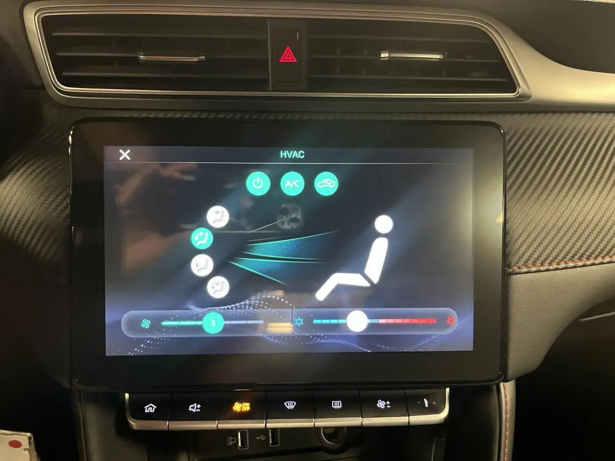 Écran tactile central affichant la climatisation dans l'habitacle du MG ZS rouge, avec tableau de bord en carbone.