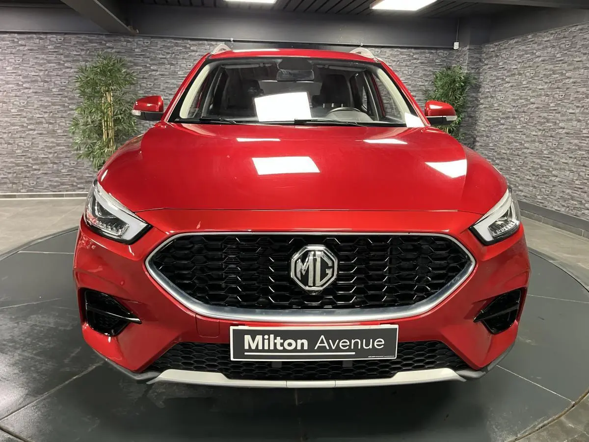 Vue frontale d'un MG ZS rouge métallisé avec calandre noire hexagonale et logo MG centré.