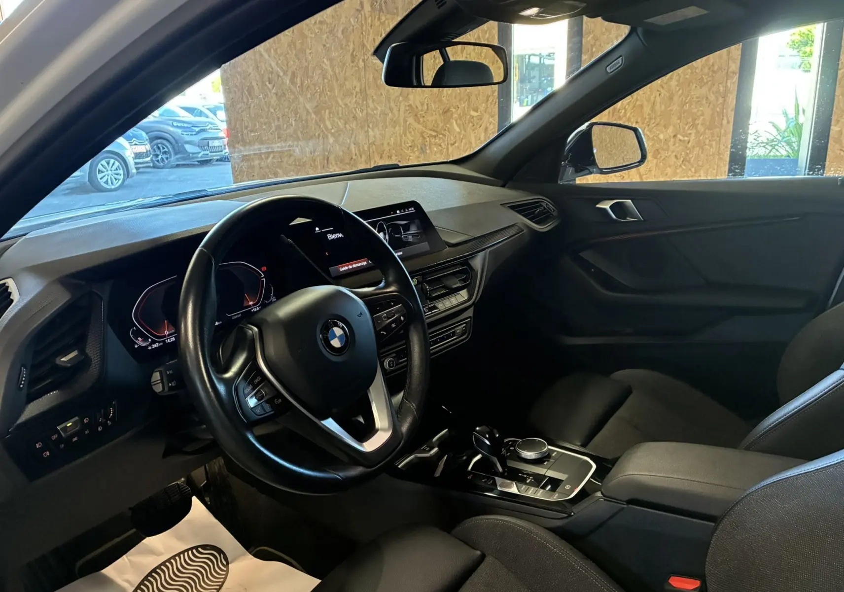 Vue intérieure côté conducteur de la BMW Série 1 118i Edition Sport 2023 avec tableau de bord et volant noir.