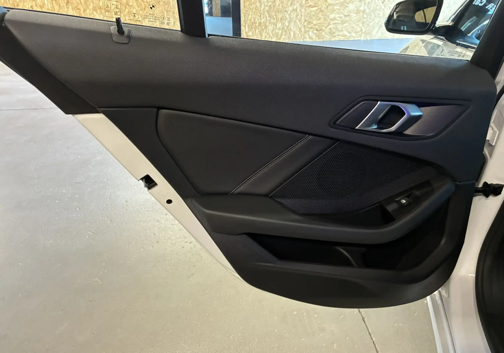 Gros plan sur la porte arrière gauche noire en tissu et plastique d'une BMW Série 1 blanche édition sport 2023.