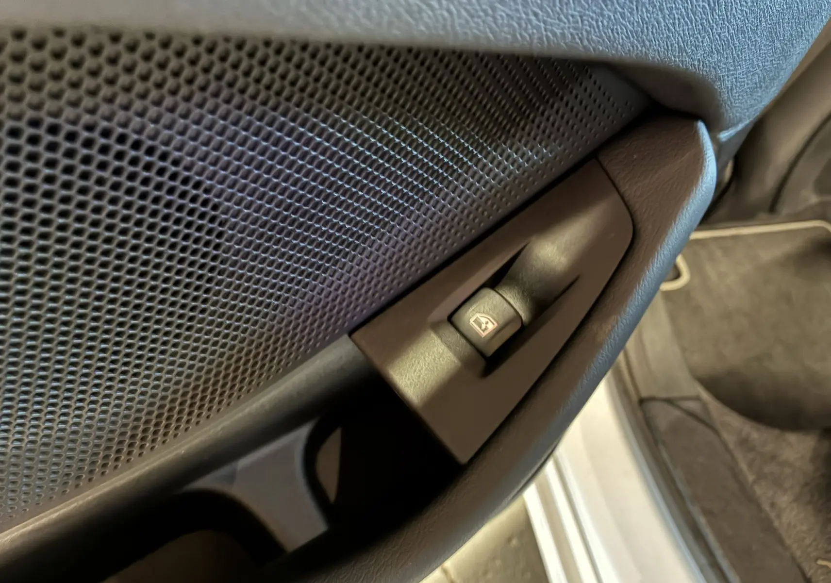 Gros plan sur le bouton de commande de la vitre côté intérieur d'une BMW Série 1 blanche, finition Edition Sport.