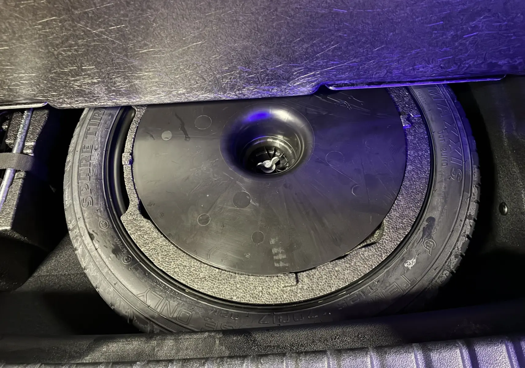 Gros plan sur la roue de secours dans le coffre d'une BMW Série 1 118i Edition Sport blanche de 2023.