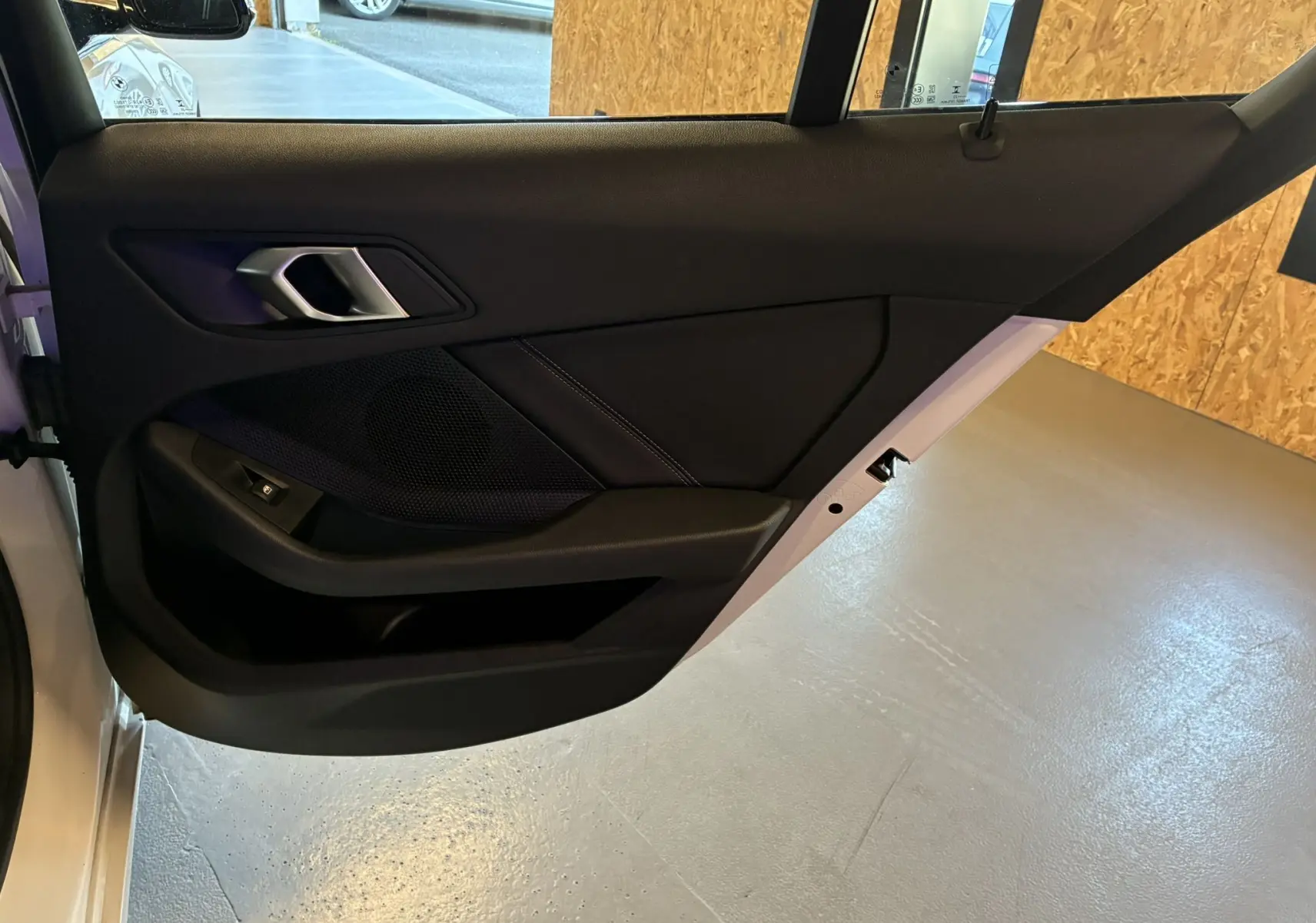 Vue intérieure de la porte arrière gauche noire d'une BMW Série 1 118i Edition Sport blanche de 2023.