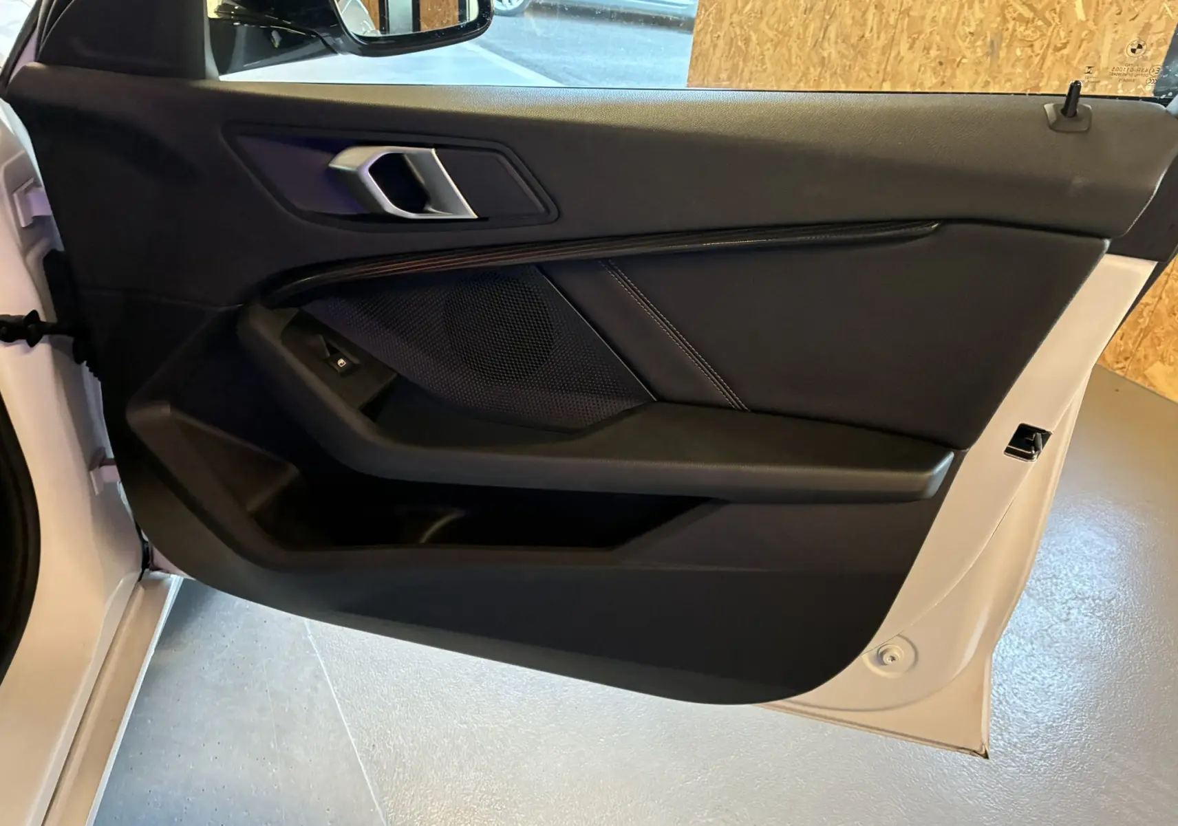 Vue côté intérieur de la porte avant gauche noire d'une BMW Série 1 118i Edition Sport blanche de 2023.