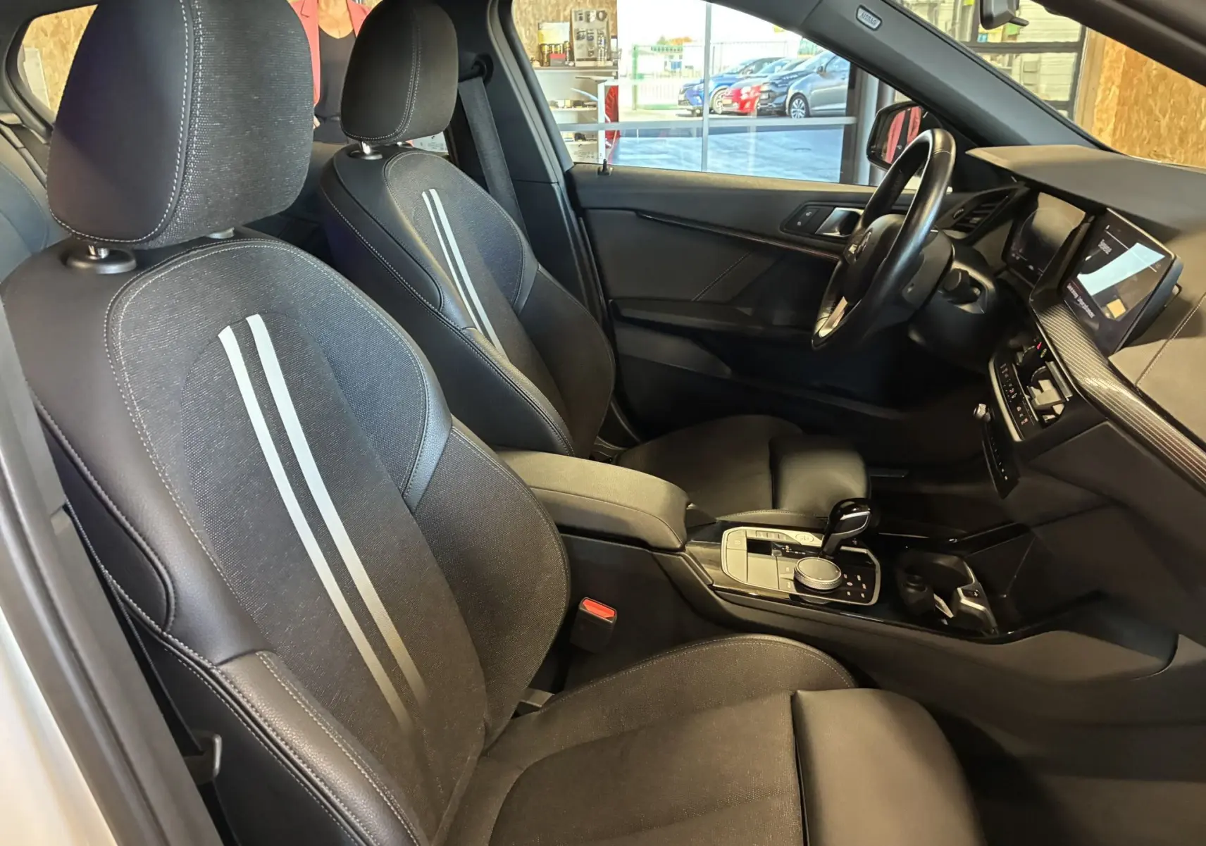 Intérieur noir de la BMW Série 1 118i Edition Sport 2023, vue côté conducteur avec sièges tissu et console centrale moderne.