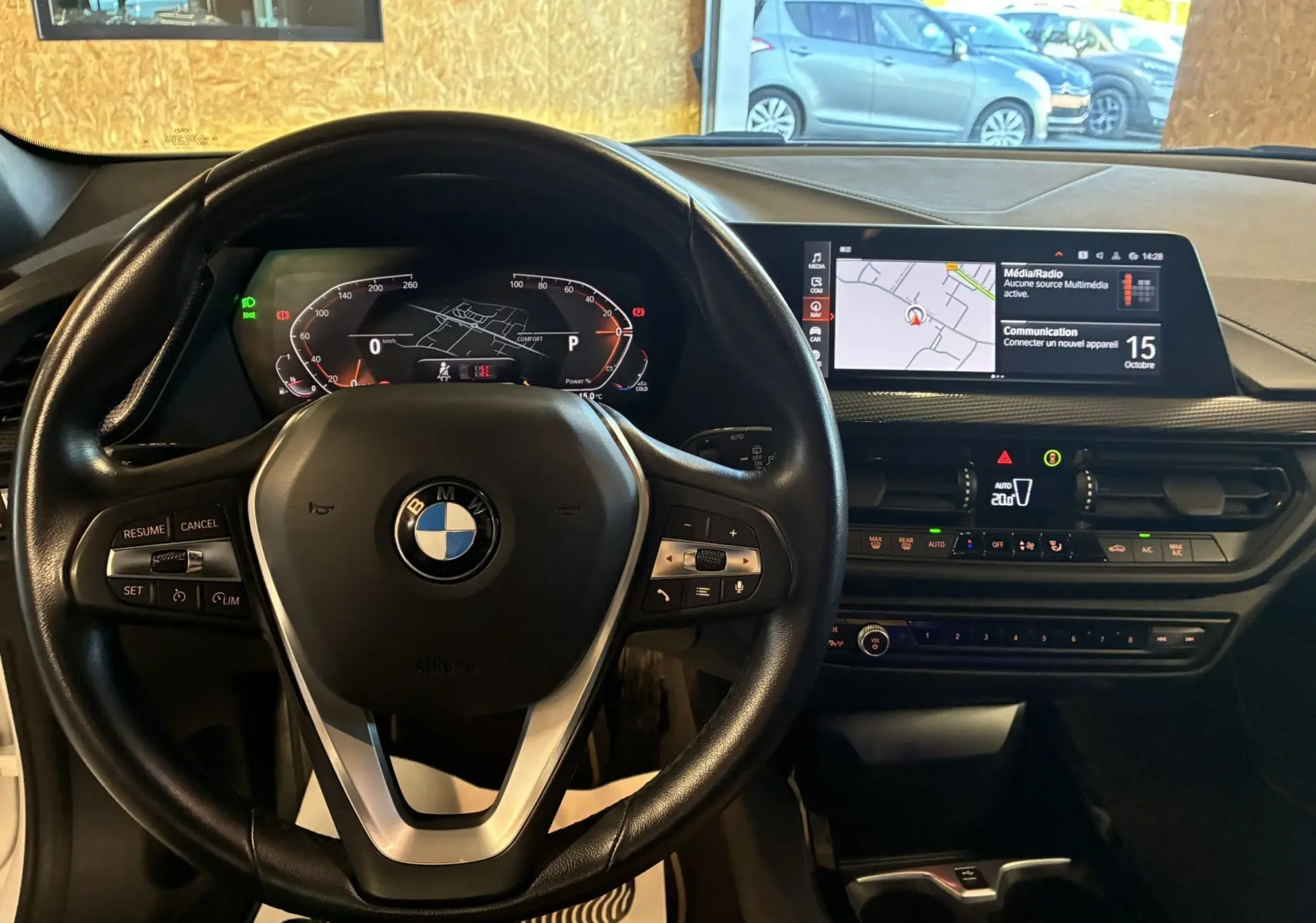 Vue intérieure de face du tableau de bord noir d'une BMW Série 1 118i Edition Sport 2023 avec écran tactile et volant multifonction.