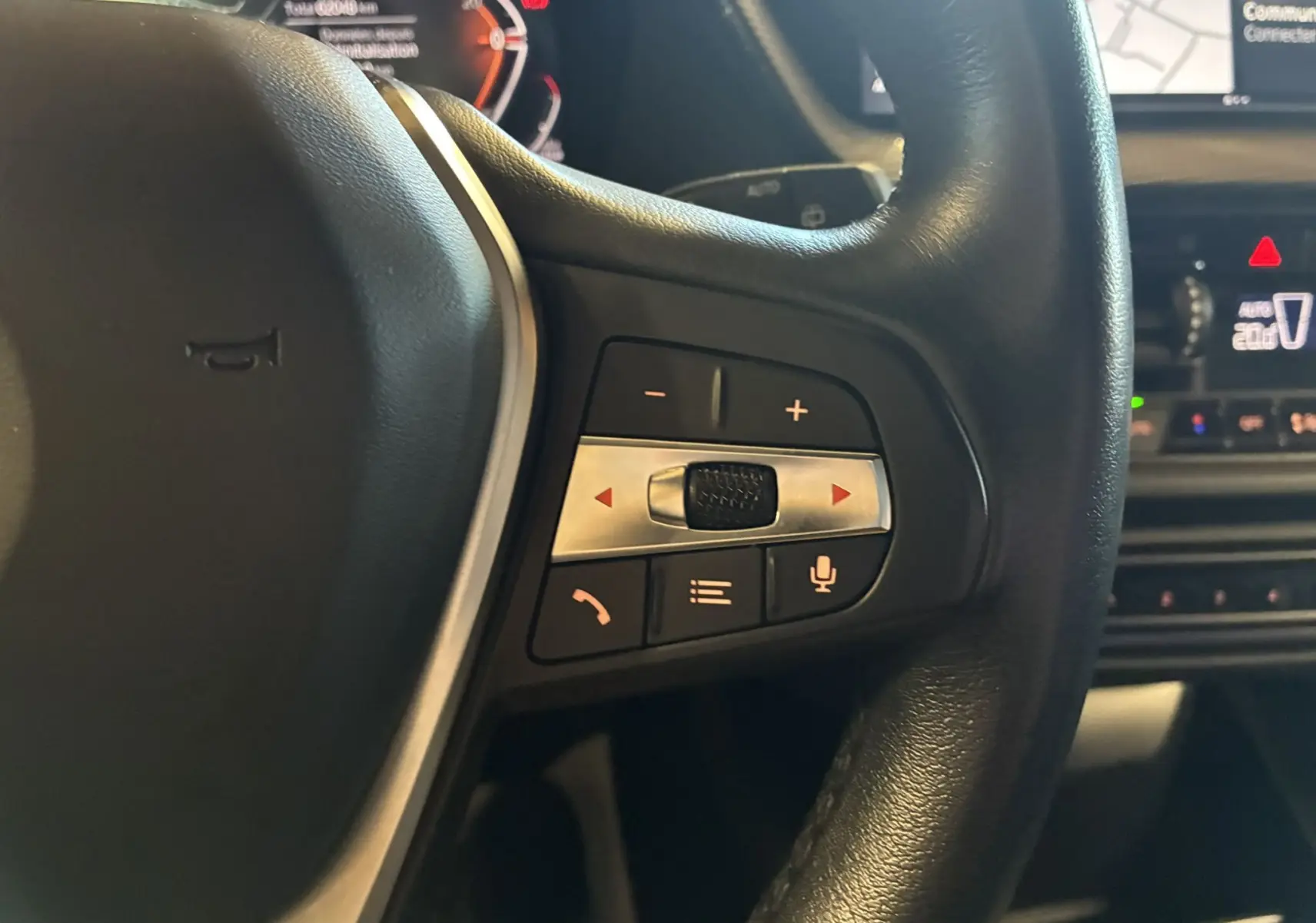 Gros plan sur les commandes multifonctions à droite du volant noir d'une BMW Série 1 118i Edition Sport 2023.