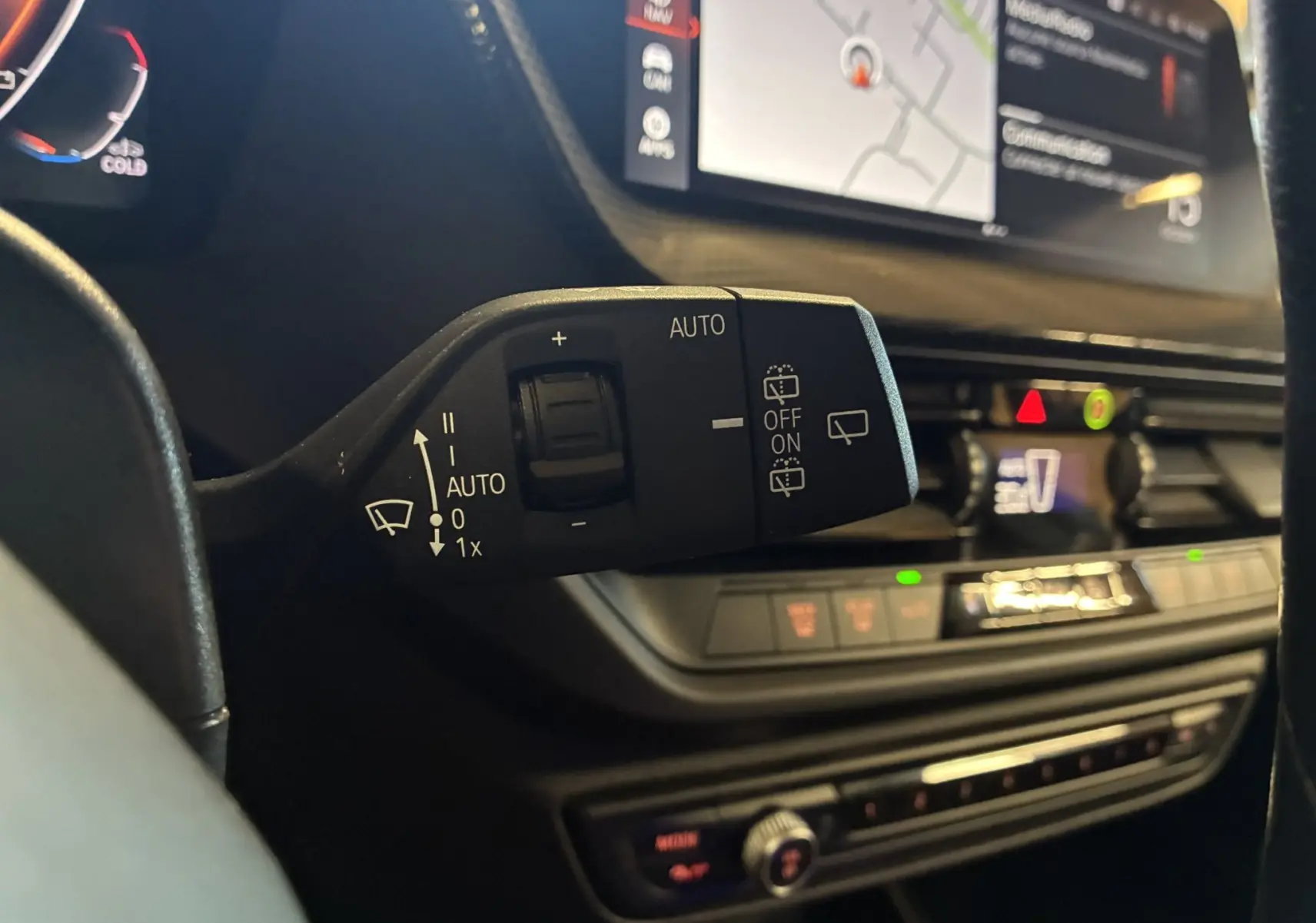 Gros plan sur la commande d’essuie-glace à gauche du volant dans l’habitacle noir d’une BMW Série 1 blanche.