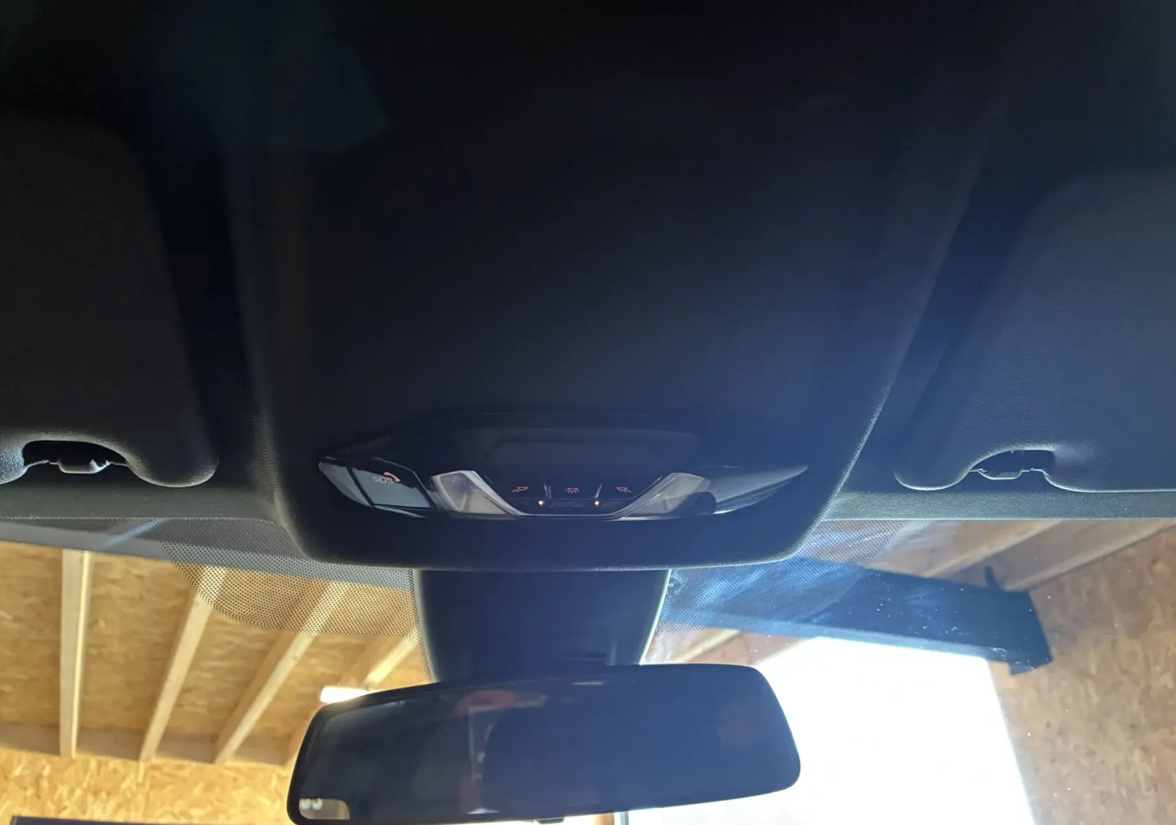 Vue intérieure du plafonnier et du rétroviseur central d'une BMW Série 1 118i Edition Sport 2023, finition noire.