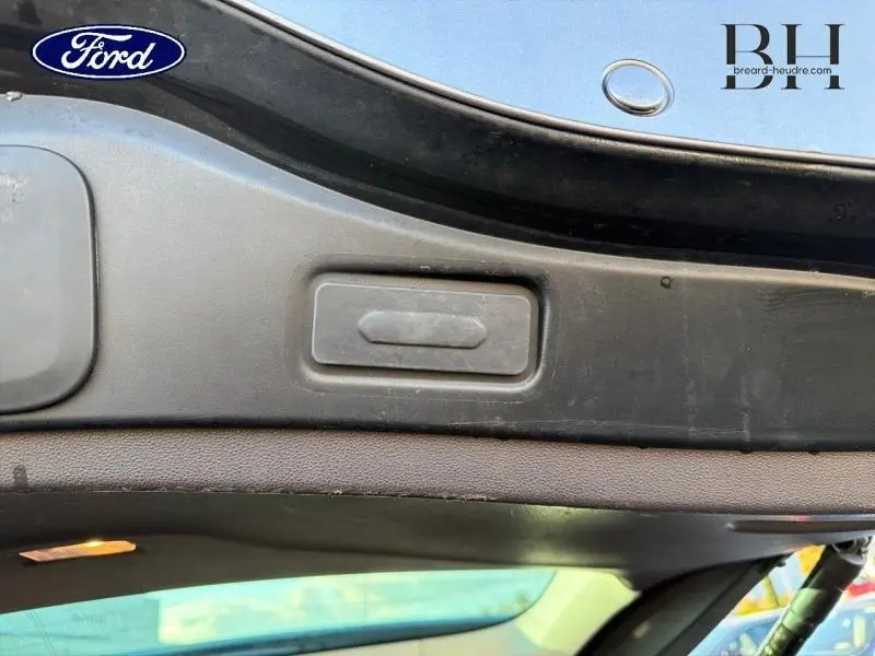 Gros plan sur le bouton d'ouverture électrique du coffre du Renault Espace gris Cassiopée, intérieur du hayon visible.