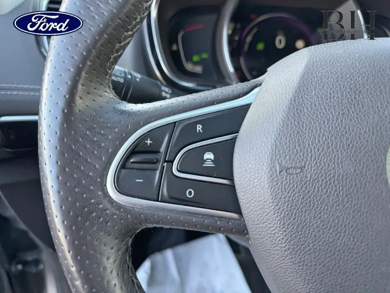 Gros plan sur le volant en cuir perforé côté gauche d'un Renault Espace gris Cassiopée, avec commandes intégrées.