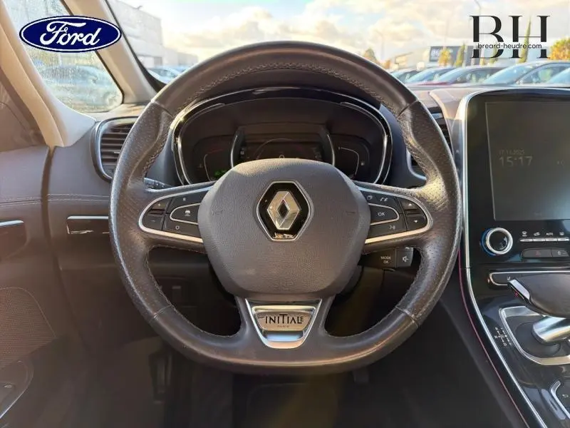 Volant cuir noir avec logo Renault et badge Initiale Paris, tableau de bord et écran tactile visibles à l'avant du véhicule.