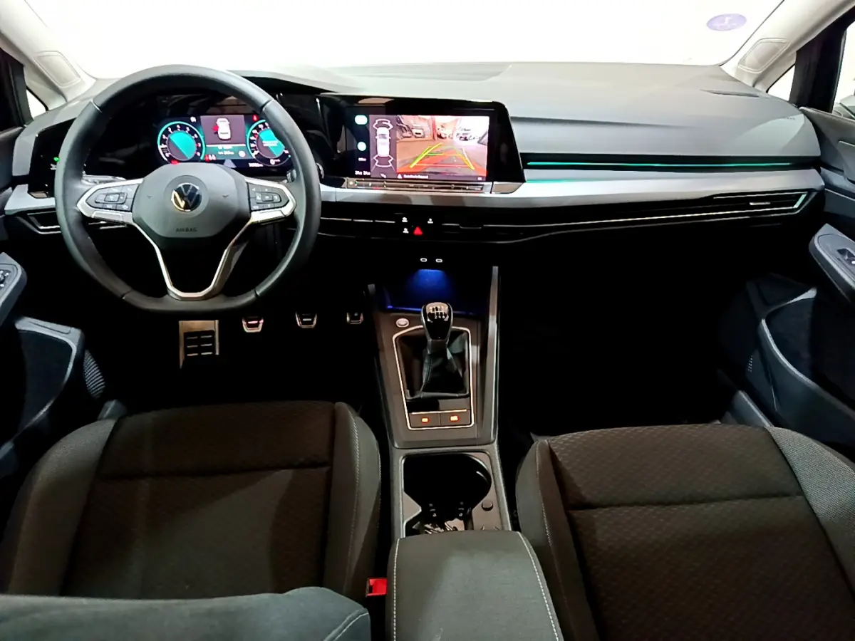 Intérieur avant de la Volkswagen Golf bleue 2022, vue du conducteur sur tableau de bord numérique et levier de vitesse manuel.