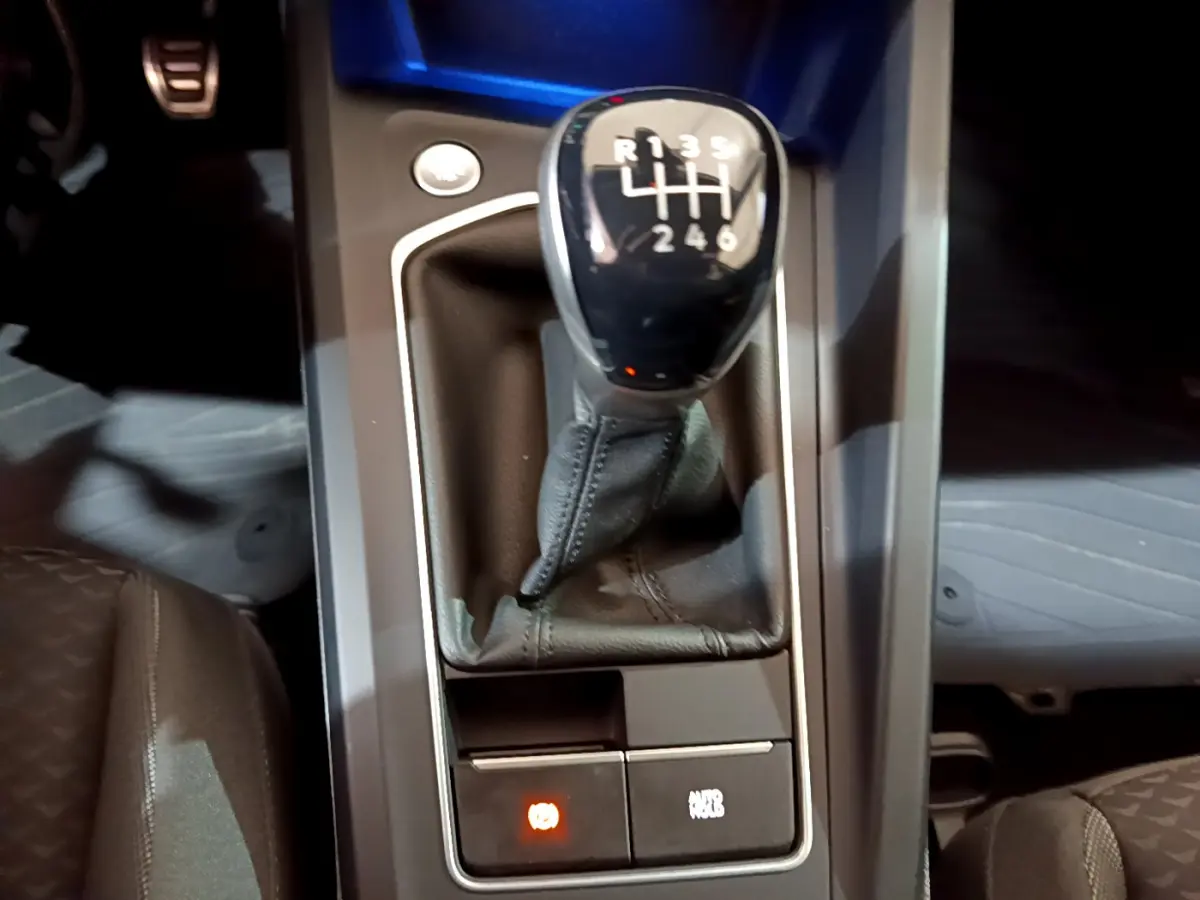 Gros plan sur levier de vitesse manuel noir dans console centrale d’une Volkswagen Golf 1.0 TSI bleu 2022