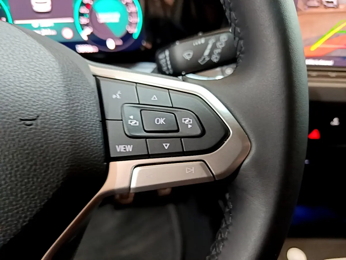 Gros plan sur les commandes au volant côté gauche d'une Volkswagen Golf bleu 2022 avec affichage numérique en arrière-plan.