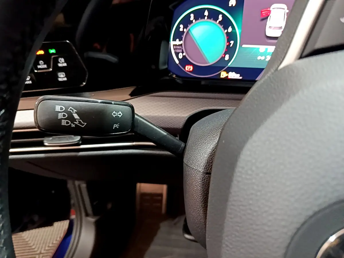 Gros plan sur la manette de clignotants et le tableau de bord numérique d'une Volkswagen Golf bleue 2022.
