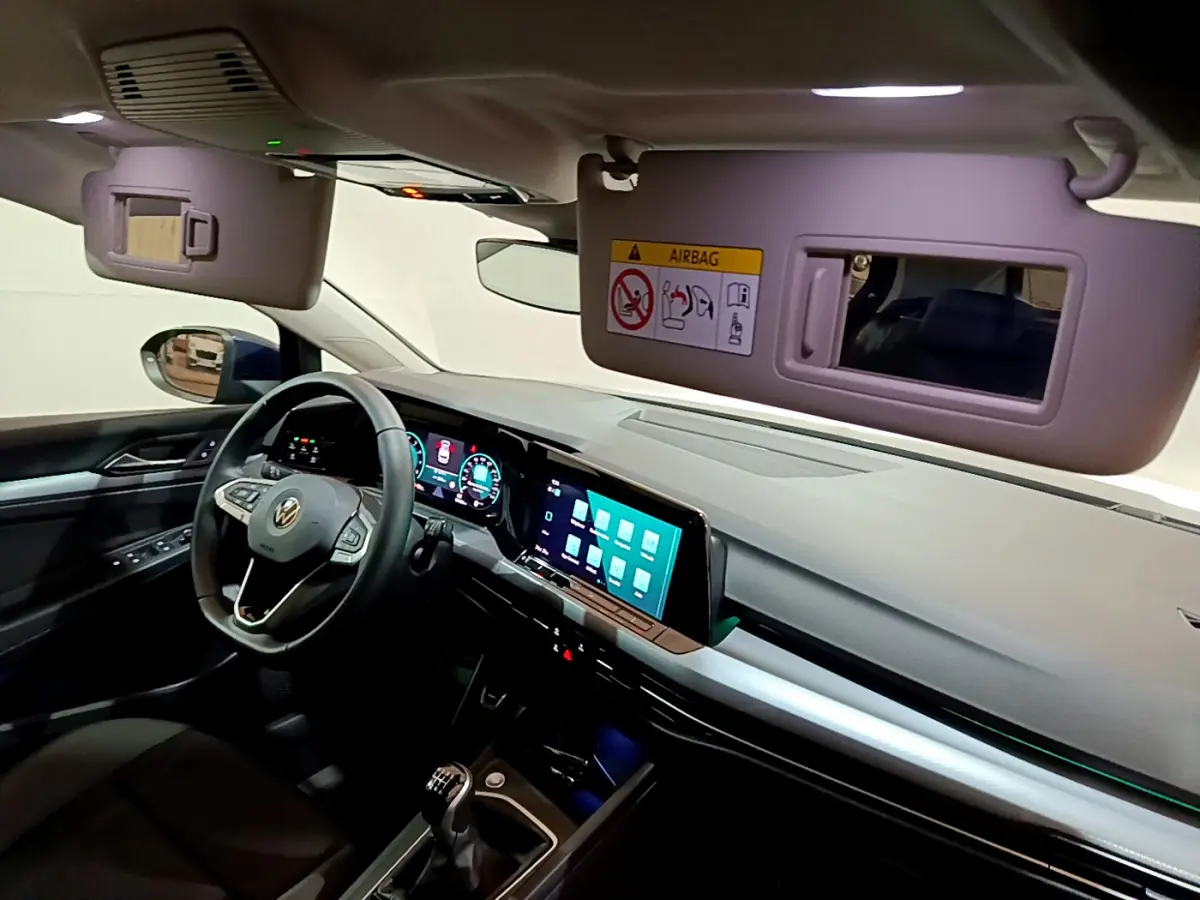 Intérieur avant gauche de la Volkswagen Golf 1.0 TSI bleu, tableau de bord digital et volant cuir multifonctions visible.