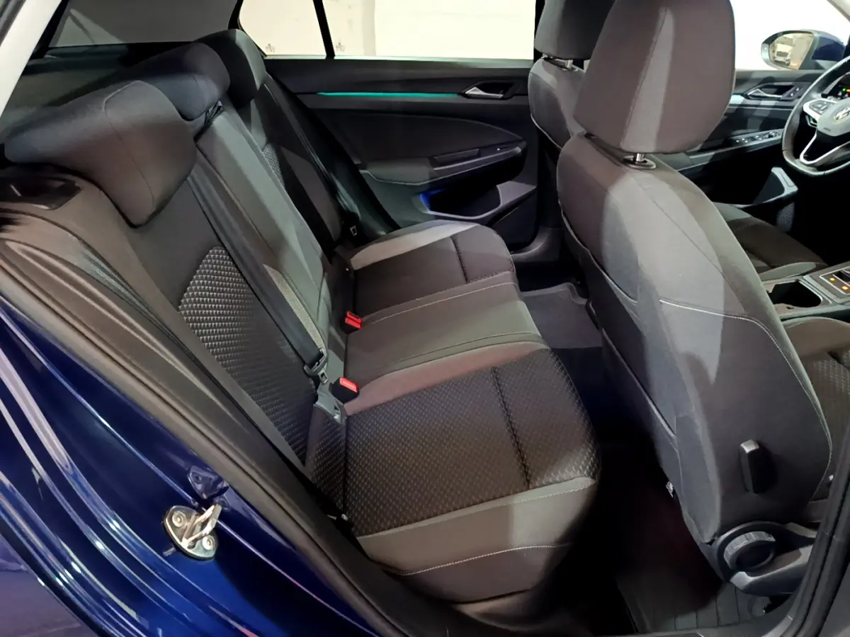Vue intérieure côté gauche montrant la banquette arrière noire et la porte bleu métallisé d'une Volkswagen Golf 2022.