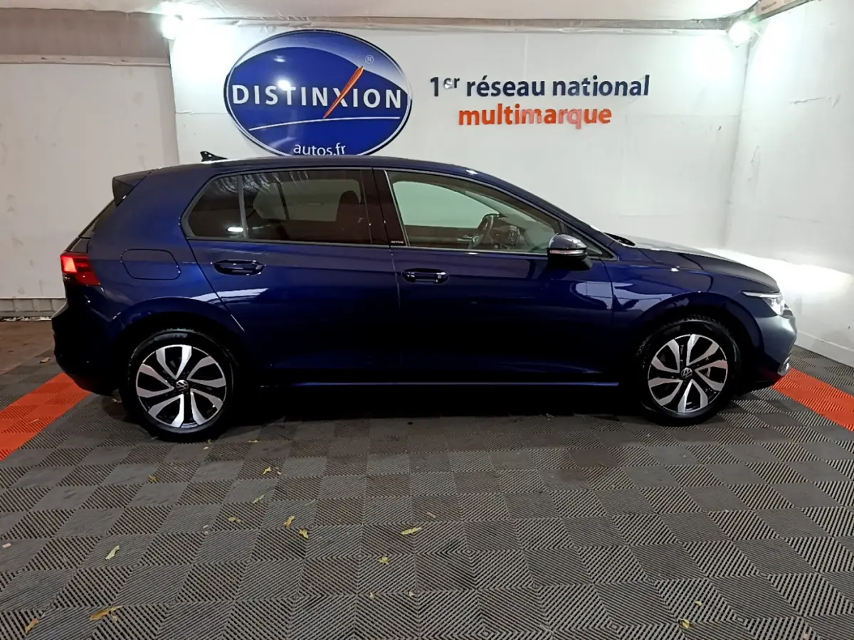Profil droit d'une Volkswagen Golf 1.0 TSI bleu foncé stationnée en intérieur avec jantes alliage distinctives.