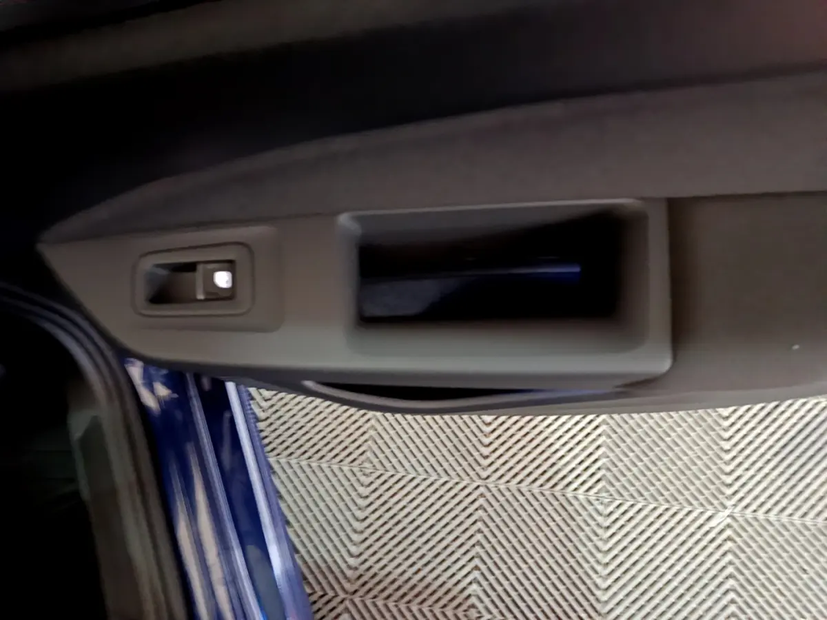 Poignée intérieure de porte côté gauche d'une Volkswagen Golf 2022 bleu, avec bouton de verrouillage visible.